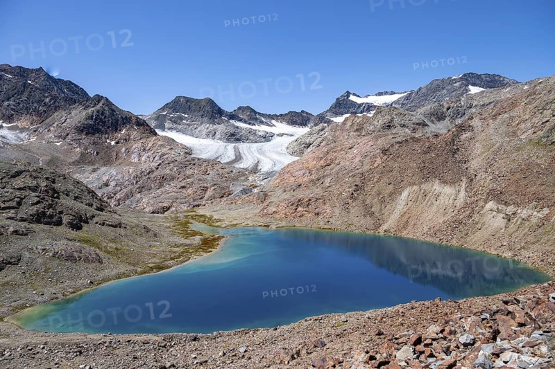 View of blue glacial lake in rocky mountain landscape, behind Königshofspitz, Schwarzwandspitz and Übeltalferner glacier, descent from summit Roter Grat, Stubai Alps, South Tyrol, Italy