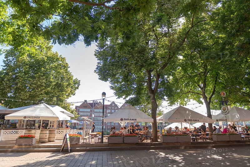 The Schlachte, historic riverside promenade along the Weser with restaurants and cafés in the shade of the trees, view of the tarred courtyard, outdoor seating area, pedestrian zone, flower pots, backlight, Old Town, Hanseatic City of Bremen, Germany