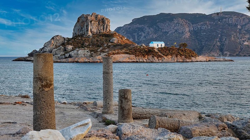 Ancient columns overlooking a rocky island with a blue house in the sea, Agios Stefanos Beach, Agios Stefanos Basilica, Basilica, Kastri Island, Kos, Dodecanese, Greek Islands, Greece