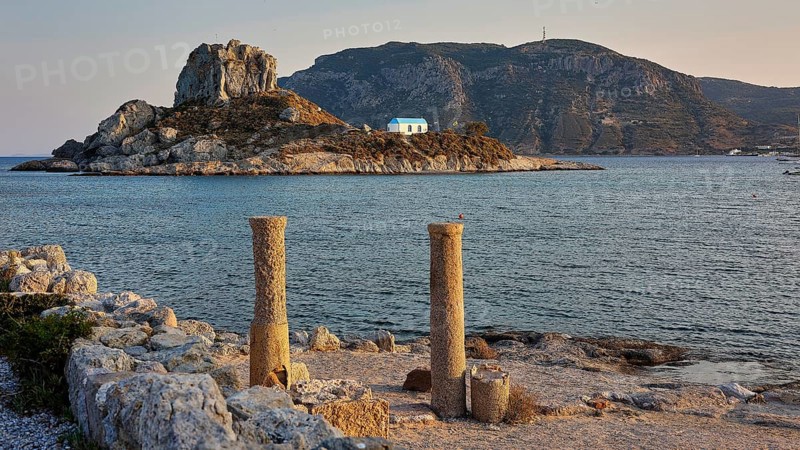 Ancient columns in front of the sea in warm evening light with an island in the background, Agios Stefanos Beach, Agios Stefanos Basilica, Basilica, Kastri Island, Kos, Dodecanese, Greek Islands, Greece
