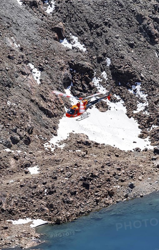 Red helicopter flying in the mountains, Stubai Alps, South Tyrol, Italy