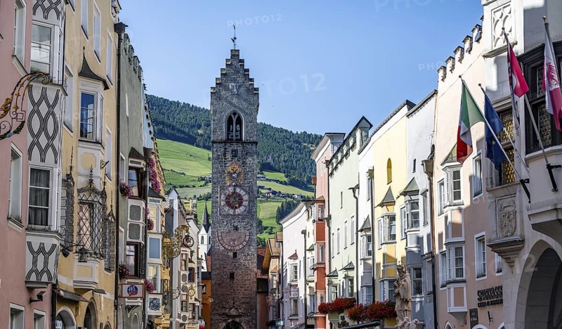 Old town, colourful houses in the main street, Zwölferturm tower at the back, old town, Sterzing, South Tyrol, Italy