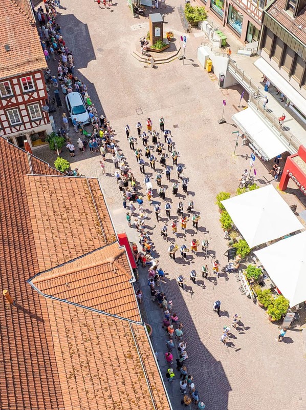 Aerial view of a parade through the alleys of a half-timbered town in sunshine with a crowd of people, 950 years of Calw, Calw parade, Black Forest, Germany