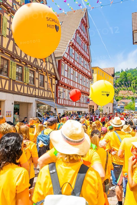 Crowd of people with orange and yellow balloons at a town festival in a half-timbered house setting, 950 years of Calw, Calw parade, Black Forest, Germany