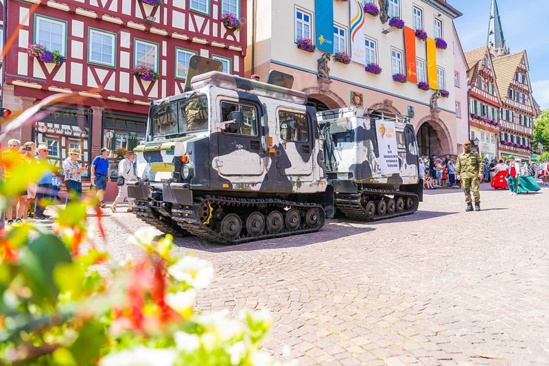 Two military vehicles in front of a row of historic half-timbered houses and surrounded by blooming flowers, 950 years of Calw, Calw parade, Black Forest, Germany