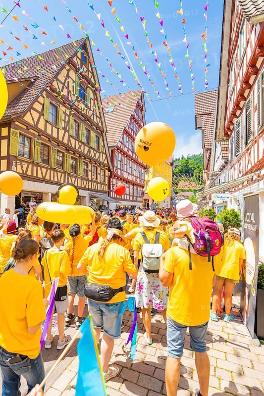 A colourful parade with yellow balloons moves through lively streets lined with half-timbered houses, 950 years of Calw, Calw parade, Black Forest, Germany