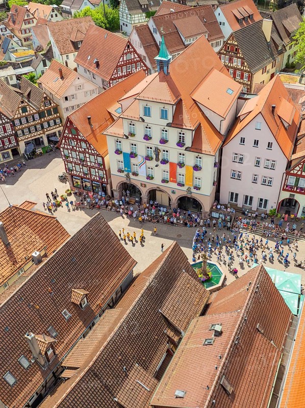 Crowd of people in front of historical buildings at a town festival, decorated with colourful flags, 950 years Calw, parade Calw, Black Forest, Germany