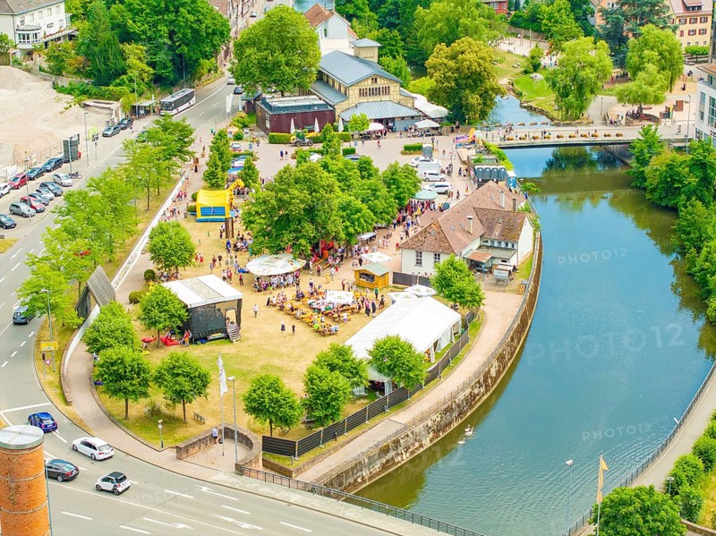 Aerial view of a small park with people, surrounded by a river and city infrastructure, 950 years of Calw, Calw parade, Black Forest, Germany