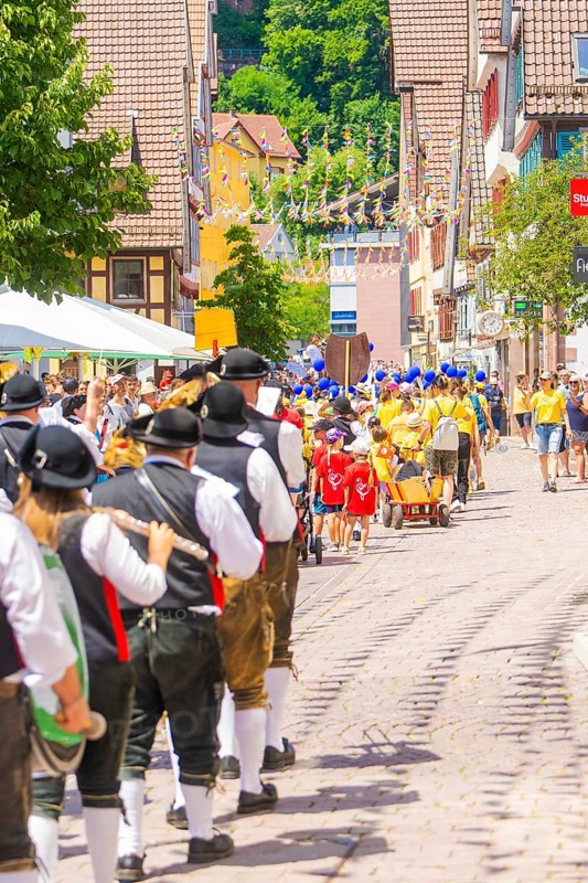 People in traditional dress parade cheerfully through a sunny village street, 950 years of Calw, Calw parade, Black Forest, Germany