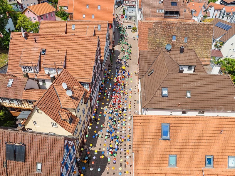 People walking on a street decorated with colourful umbrellas, 950 years Calw, parade Calw, Black Forest, Germany
