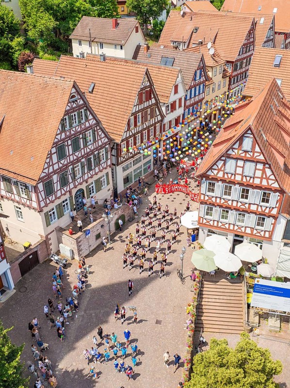 A large crowd gathers in front of half-timbered buildings during a colourful parade, 950 years of Calw, Calw parade, Black Forest, Germany