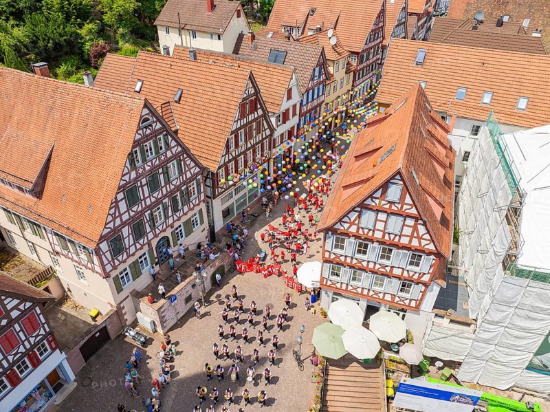 From above you can see people in formation and colourful balloons next to historic house facades, 950 years of Calw, Calw parade, Black Forest, Germany