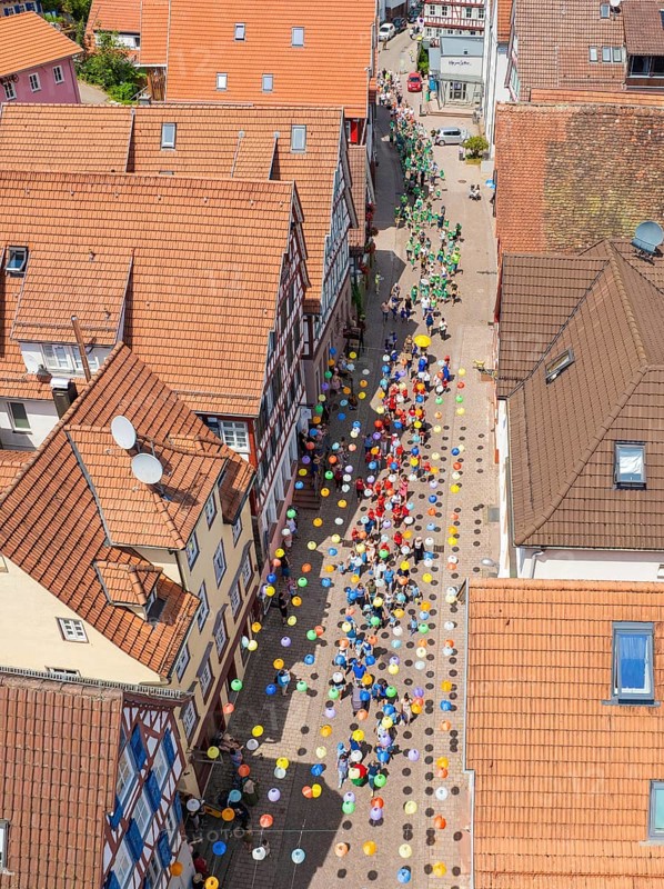 Colourful balloons decorate a busy street, surrounded by houses with red tiled roofs, 950 years of Calw, Calw parade, Black Forest, Germany