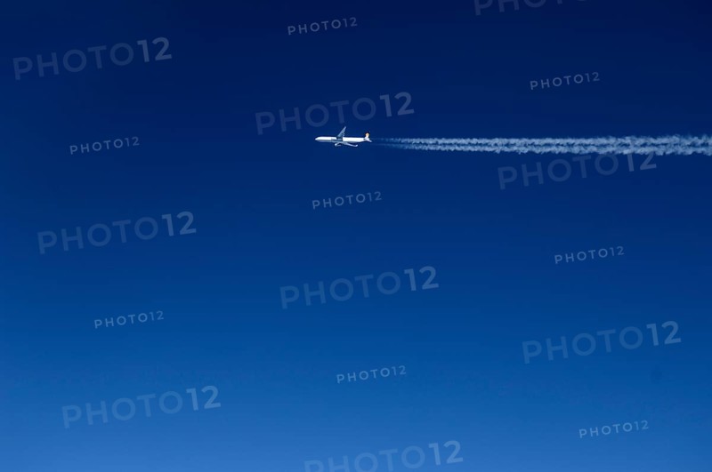 View of a passing aircraft in the blue sky at an altitude of 10, 000 metres, Atlantic flight to New York, USA
