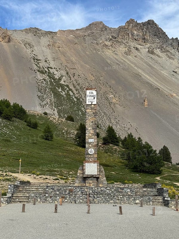 At Alpine pass Col de l'Izoard d'Izoard 2360 metres high road pass at pass summit of mountain road pass road 1934 erected altitude marker monument stele memorial column made of natural stone in memory of dedicated to General Baron Berge and workers of road construction, Cervières, Department Hautes-Alpes, Provence-Alpes-Cote d'Azur, France