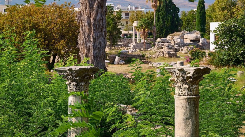 Two ornate ancient columns rise out of lush green foliage in a landscape of ruins, Ancient Agora, Kos Town, Kos, Dodecanese, Greek Islands, Greece