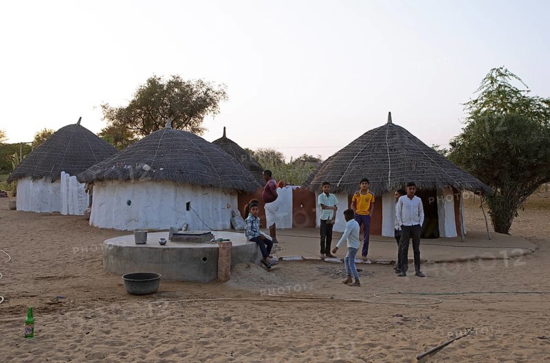 Indian desert dwellers, behind typical circular buildings in the Thar Desert or Great Indian Desert, near Jaisalmer, Rajasthan, India