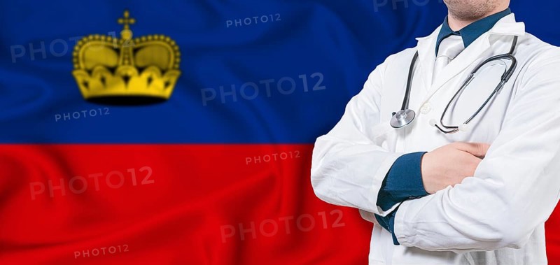 Liechtenstein healthcare concept. Male doctor on Liechtenstein flag. Doctor with crossed arms on Liechtenstein flag