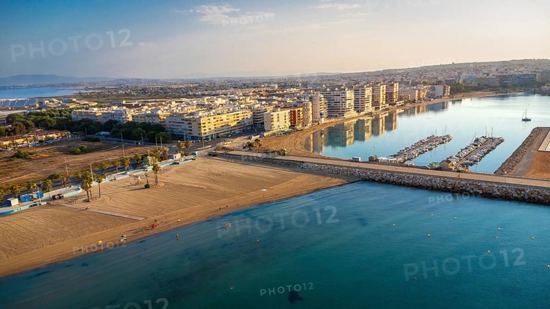 Aerial view of torrevieja coastline reflecting in mediterranean sea at sunrise, featuring acequion and naufragos coves, buildings, beaches, and harbor