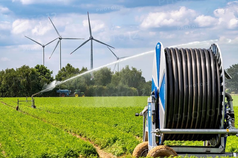 Artificial irrigation with a sprinkler system in a field where carrots are grown, hose reel, wind farm, near Kerken, on the Lower Rhine, North Rhine-Westphalia, Germany