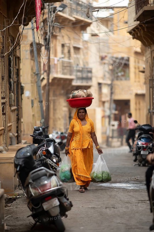 Indian woman carrying a bowl on her head in the old town of Jaisalmer, Rajasthan, India