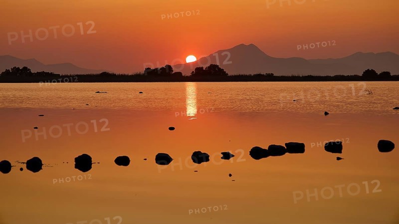 Warm sunset light reflected in the calm lake with mountain backdrop, salt lake, Tigaki, nature reserve, hydro biotope, Kos, Dodecanese, Greek Islands, Greece