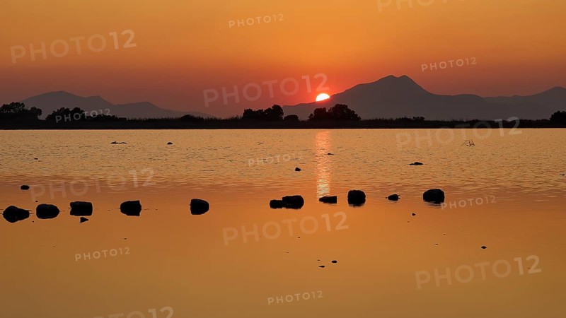 Idyllic scene with setting sun behind a lake and mountains, salt lake, Tigaki, nature reserve, hydro biotope, Kos, Dodecanese, Greek Islands, Greece