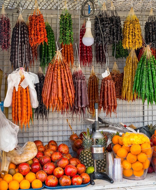 A market stall full of colorful fruits and traditional sweets with a juicer in the foreground, Churchkhela hanging, Georgian confectionery, 'Georgian snickers', Batumi, Black Sea, Ajara region, Adjara, autonomous republic, Georgia