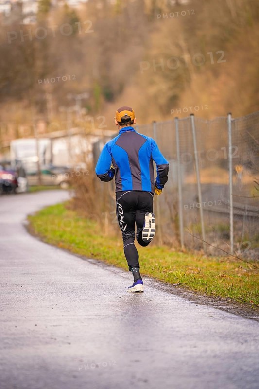 Man running on asphalt road wearing blue and black sportswear, triathlon, Calw, Germany