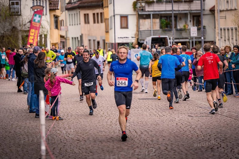 Runners and spectators on a paved road during a road race, triathlon, Calw, Germany