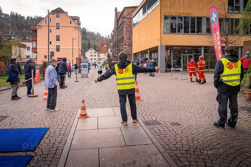 Group of people wearing safety vests at a roadblock in an urban environment, triathlon, Calw, Germany