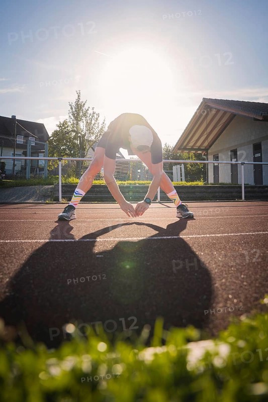Person stretching on a running track at sunset, triathlon, Calw, Germany