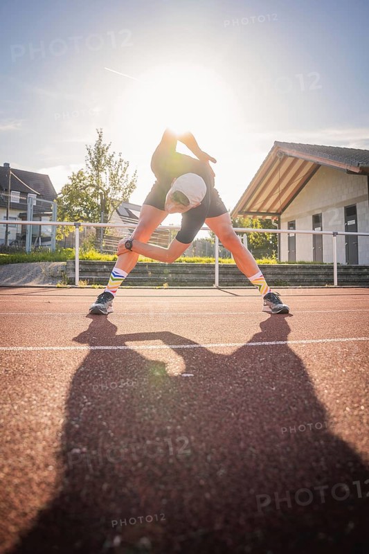 Runner stretching on a running track in sunshine, Triathlon, Calw, Germany