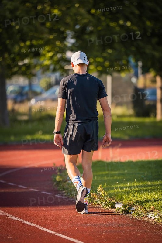 Athlete walks comfortably on a running track in diffuse sunlight, Triathlon, Calw, Germany