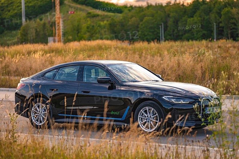 Black car in a field with natural surroundings and road layout, BMW i7 electric car, Deer e-Carsharing, Calw, Germany