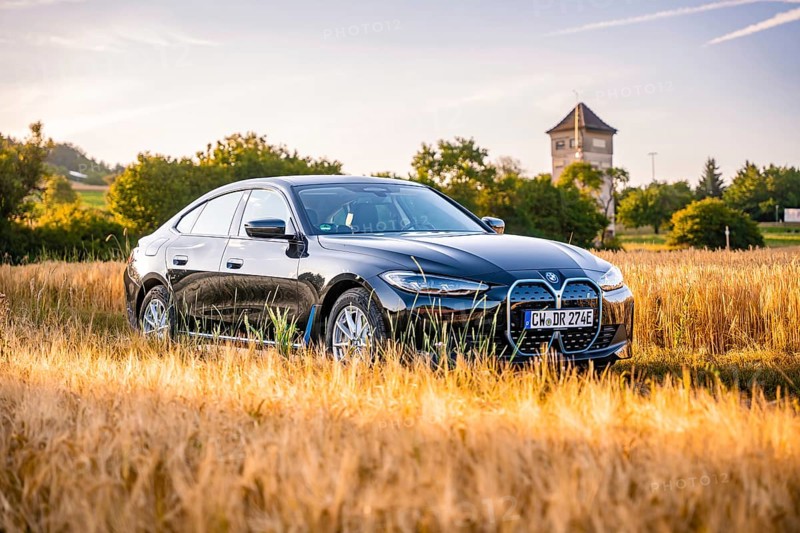Black electric car in a cornfield, a tower in the background, summer landscape at sunset, BMW i7 electric car, Deer e-Carsharing, Calw, Germany