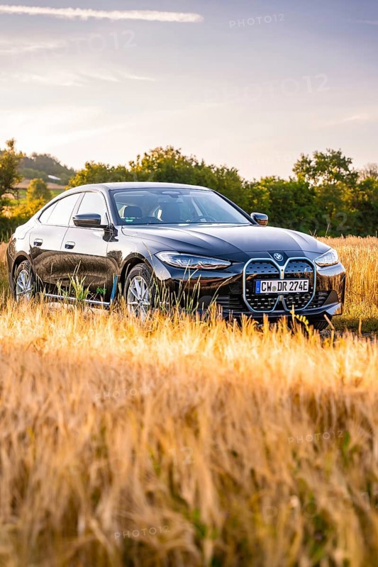 Black electric car in a cornfield at sunset, surrounded by a golden evening mood, BMW i7 electric car, Deer e-Carsharing, Calw, Germany