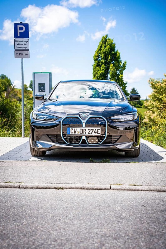 A black car is parked at a charging station with clear blue sky, BMW i7 electric car, Deer e-Carsharing, Calw, Germany