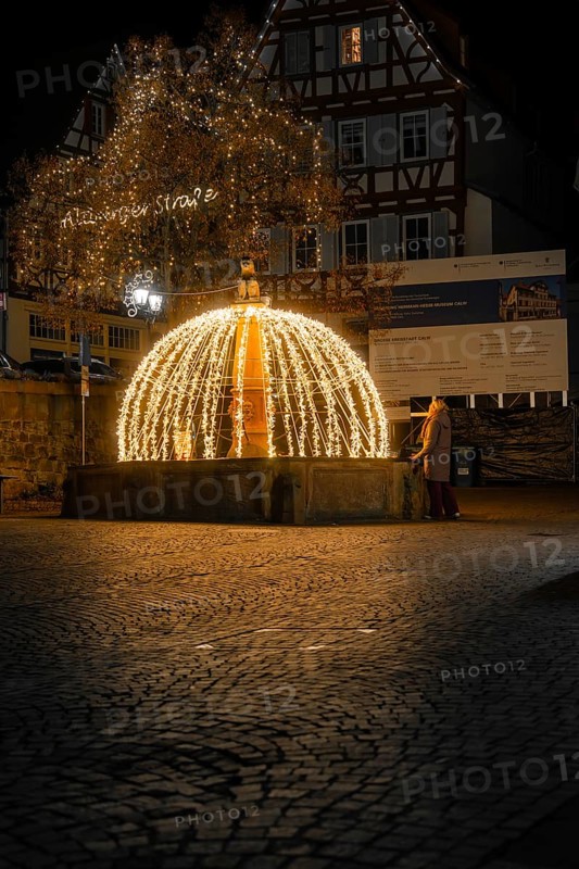 Atmospheric illuminated fountain at night in a paved old town scenario, Calw, Black Forest, Germany