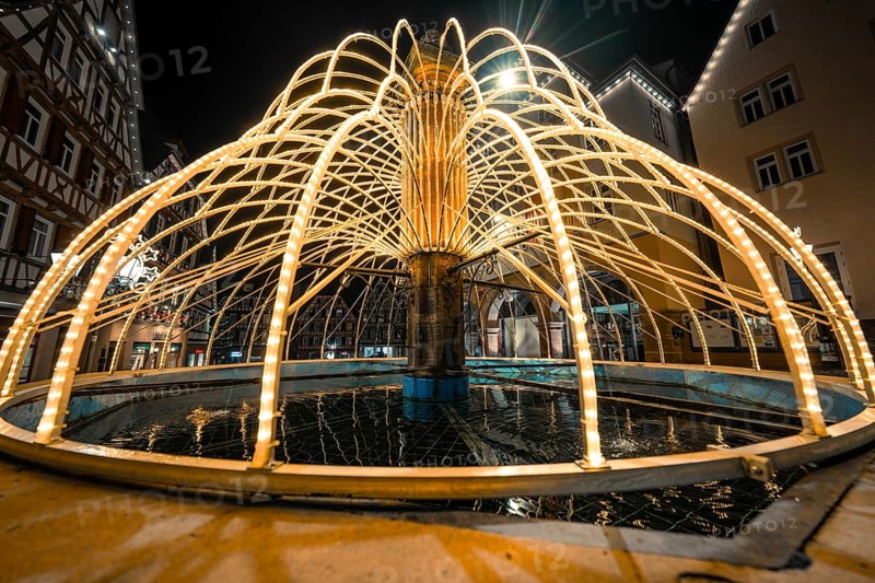 Close-up view of illuminated fountain with reflections in water, Calw, Black Forest, Germany