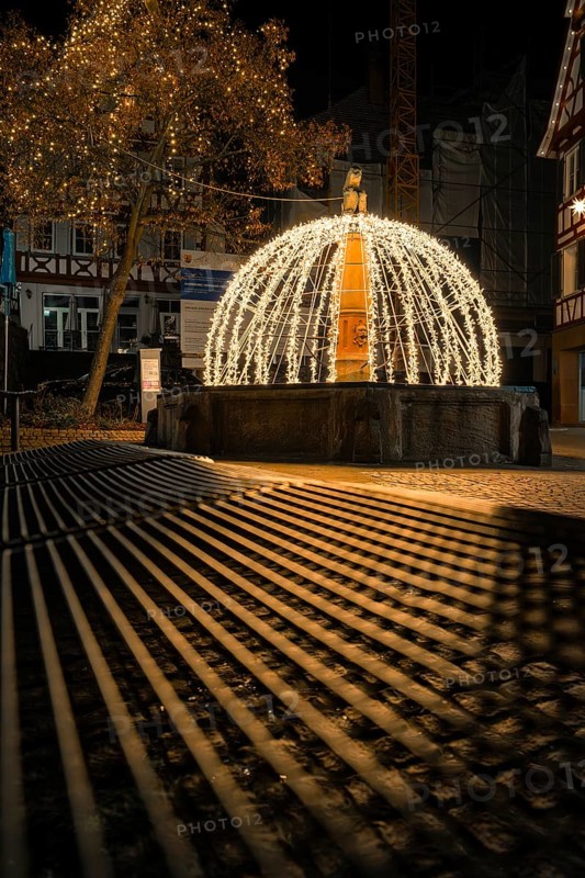 Atmospheric night view of a festive fountain with lights and shadows in an old town, Calw, Black Forest, Germany