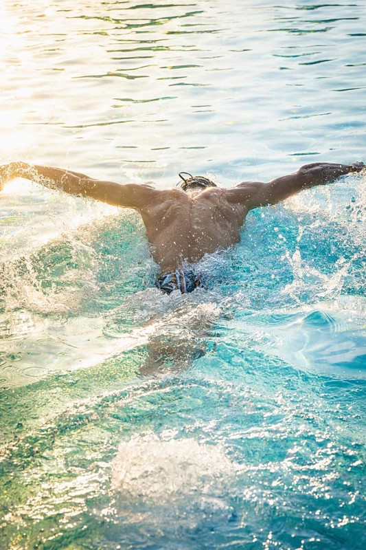 A swimmer in a pool laps in sunlight and whirls up water, triathlon, Calw, Germany
