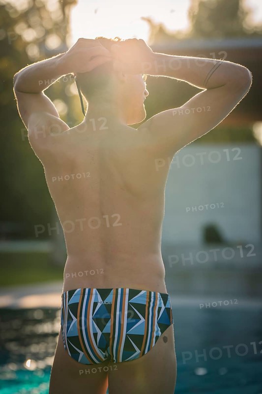 A man in swimming trunks stands by the pool in sunlight and enjoys the relaxed atmosphere, Triathlon, Calw, Germany