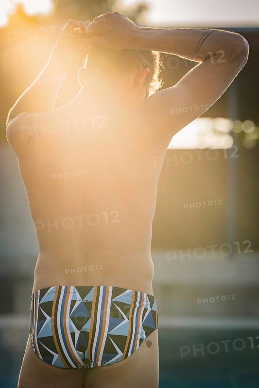 Man wearing colorful swim trunks enjoying the sun at the edge of the pool, Triathlon, Calw, Germany