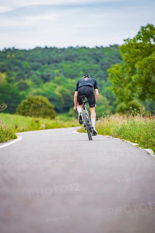 Cyclist climbing a road in hilly countryside surrounded by greenery, triathlon, Calw, Germany
