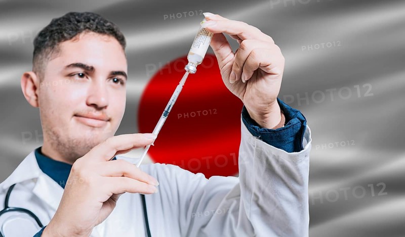 Doctor holding syringe on Japan flag background. Medical professional holding syringe with Japanese flag in the background