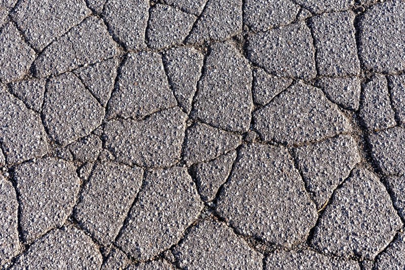 Asphalt surface, floor, with many small cracks, roadway, parking lot