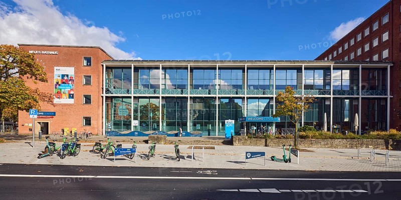 New town hall, tourist information, welcome center, brick building, modern building, glass façade, staircase, concrete paving walkway, e-scooter rental, sprat fleet bike sharing Kiel region, e-scooter, bicycles, road, road marking direction arrow, blue sky, cumulus clouds, Andreas-Gayk-Straße, Stresemannplatz, Kiel, state capital, district-free city, Schleswig-Holstein, Germany