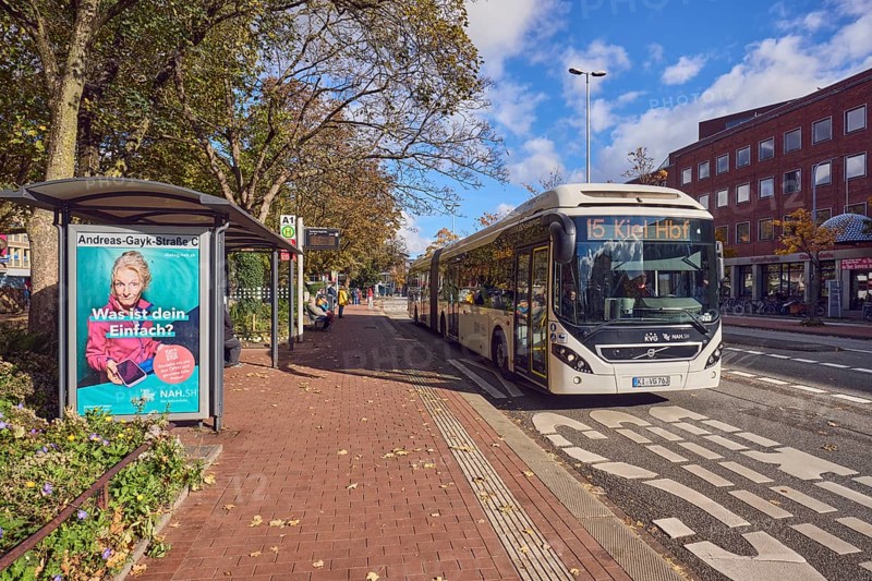 Andreas-Gayk-Straße C bus stop, bus line 15 to Kiel Hbf, Kieler Verkehrsgesellschaft, bus lane, bus shelters, advertising poster, advertisement NAH.SH Public transport, road marking BUS, people waiting for means of transport, lantern, trees, autumn leaves, general architecture, blue sky, cumulus clouds, Andreas-Gayk-Straße, Kiel, state capital, district-free city, Schleswig-Holstein, Germany
