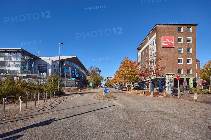 Wunderino Arena multi-purpose hall, general architecture, brick buildings, residential buildings and commercial buildings, advertising flags on flagpoles, advertising drink Coca-Cola, neon sign, lantern, barrier bollard, central island, traffic sign prescribed direction right past, cyclists as secondary motif, blue sky, cloudless, intersection of Kleiner Kuhberg, Waisenhofstraße and Europaplatz, Kiel, state capital, district-free city, Schleswig-Holstein, Germany